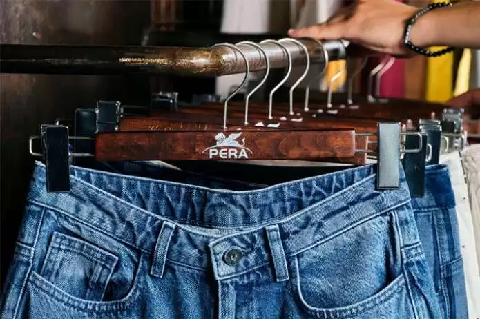 Pera Tekstil web sitesi projesini anlatan liste görseli, fotoğrafta askıda asılı duran denim pantolonlar ve askıdaki Pera logosu görünmektedir.